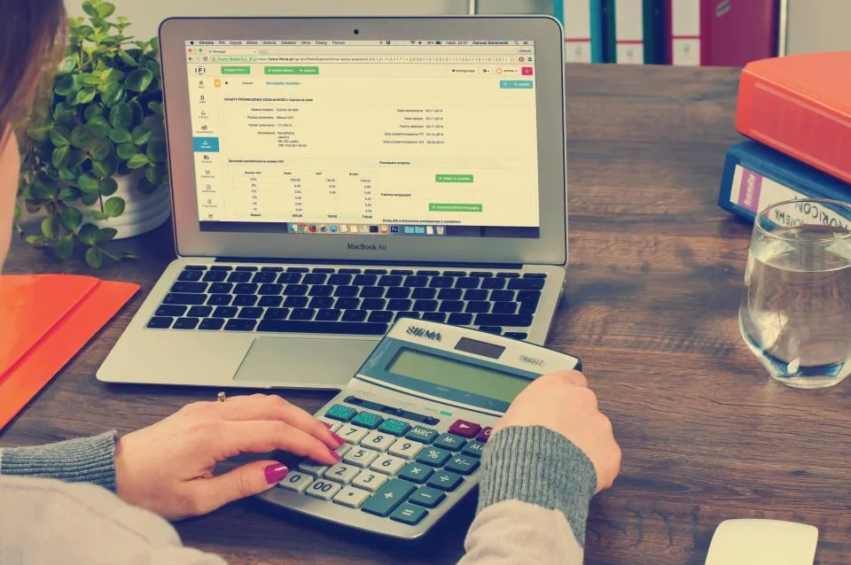 Portátil con una hoja de cálculo y una calculadora sobre la mesa
